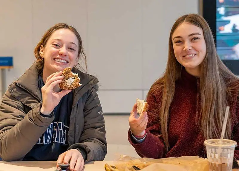 Two students happily enjoying bagel