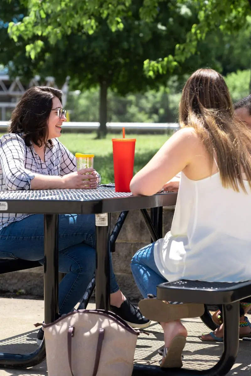 people sitting at an outdoor table with to-go cups