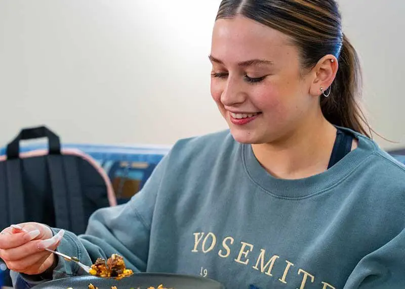 Student happily eating a bowl of food