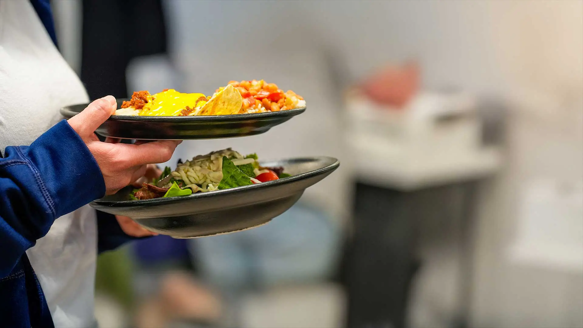 Hands holding plates of food