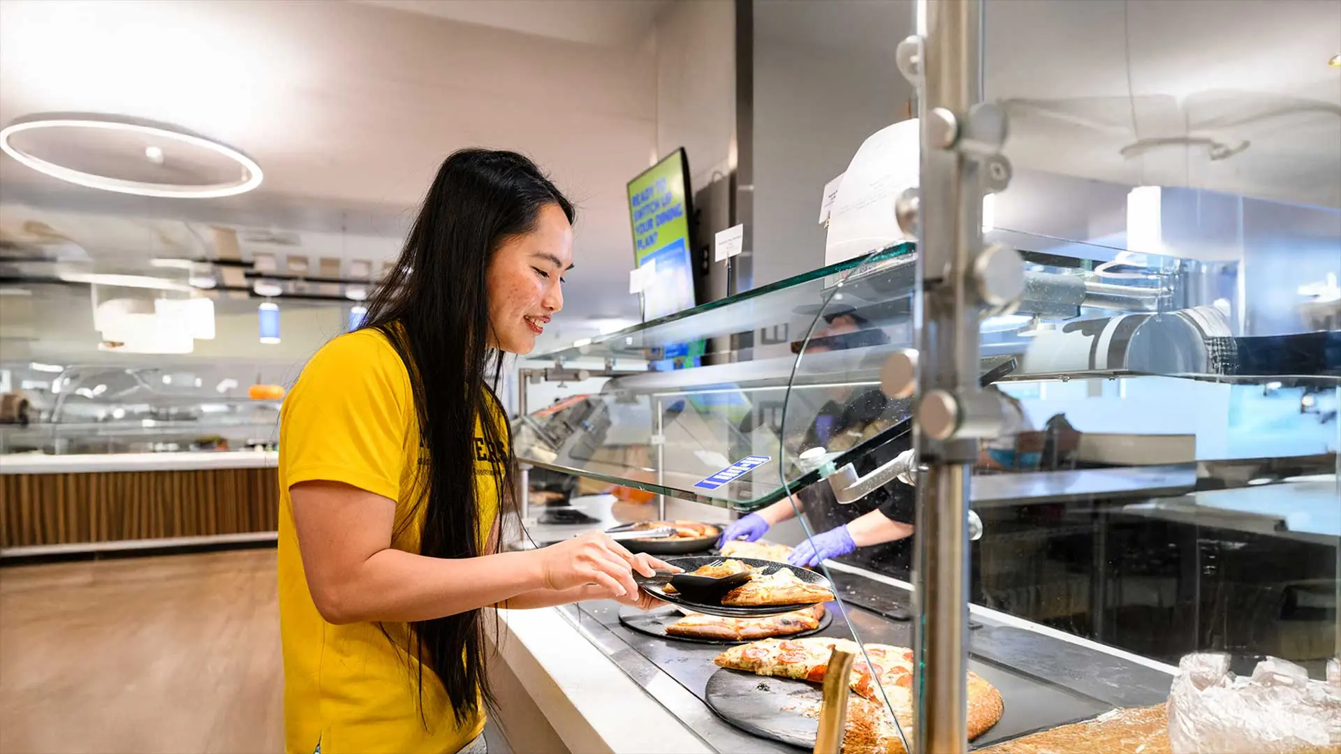 Student happily getting pizza from serving line